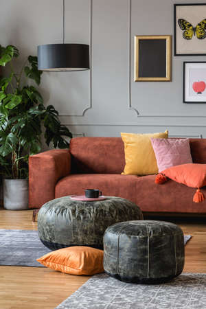 Vintage black poufs in trendy eclectic living room interior with brown couch
