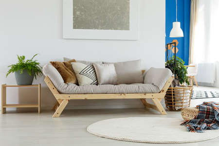 Classy living room interior with beige Scandinavian sofa with pillows, silver abstract painting on the wallの写真素材
