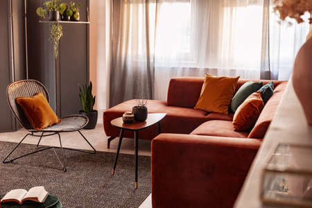 Small coffee table in front of comfortable corner sofa in autumn colored living room interiorの写真素材