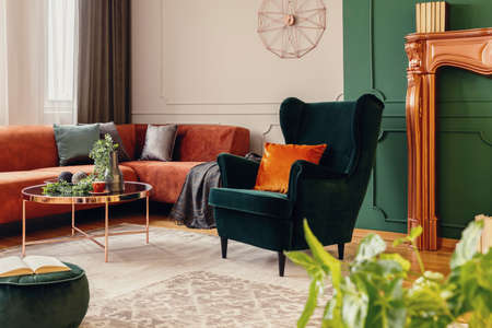 Brown velvet corner sofa and emerald green wing back chair in classy living room
