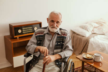 Senior man sitting lonely on a wheelchair at home