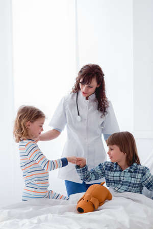 Two kids playing together next t the young nurse in a hospitalの写真素材