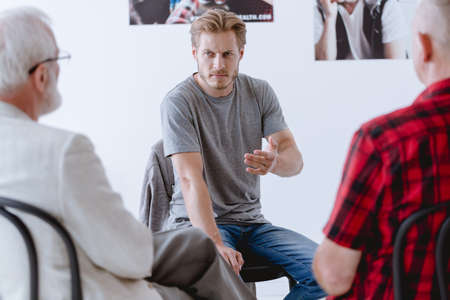 Young man during group psychotherapy talking about his feelingsの写真素材