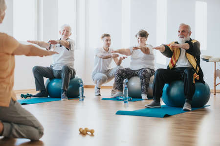 Group of senior people exercising on balls together in a gymの写真素材