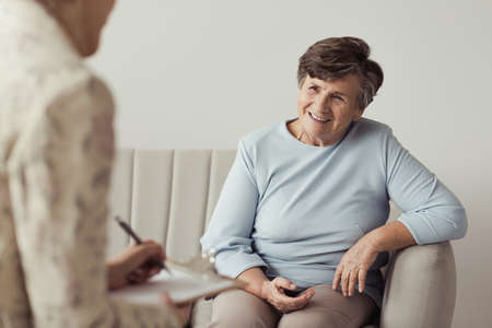 Smiling senior female talking to a therapistの写真素材