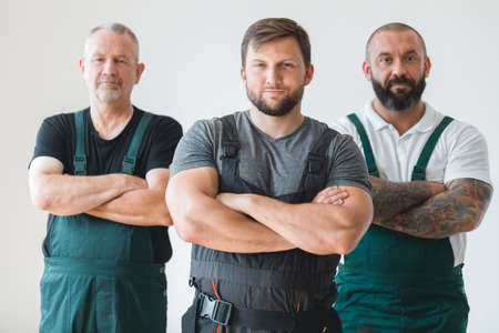 Crew of three professional builder wearing overalls standing in empty interiorの写真素材