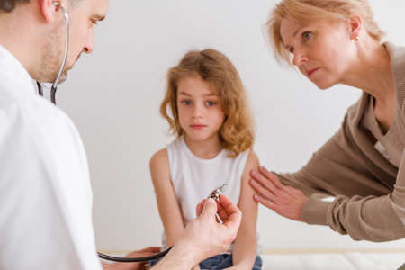 Kids doctor auscultating little sick girl in the hospitalの写真素材