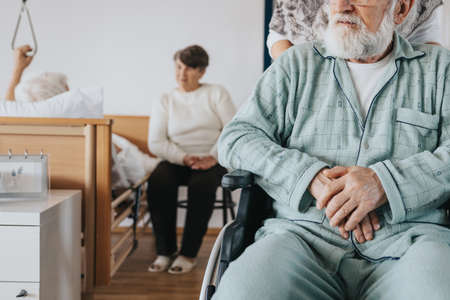 Senior man after stroke sits in a wheelchair at a nursing homeの写真素材