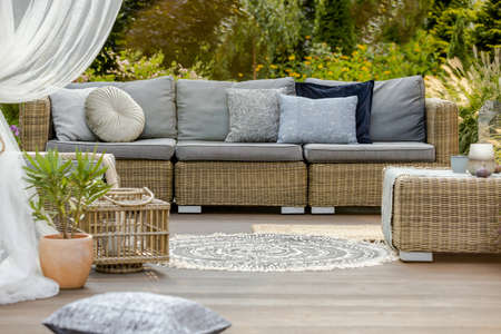 Modern wooden porch with rattan furniture outside the houseの写真素材