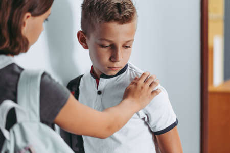 Young friendly boy helping worried and sad boy at schoolの写真素材