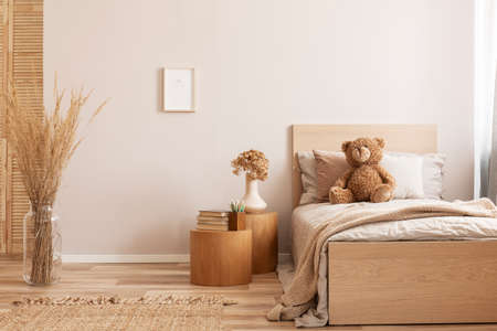 Bright and natural hotel room interior with single bed and wooden nightstand with flowersの写真素材