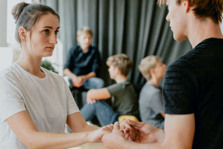 Teenage boy holding girl's hands and talking about his feelings