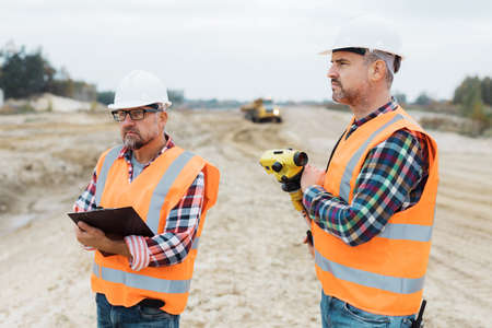 Two road construction workers using measuring device on the field