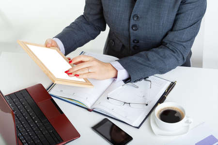 Overworked businesswoman sitting at desk with open calendar and laptop and working on tabletの写真素材