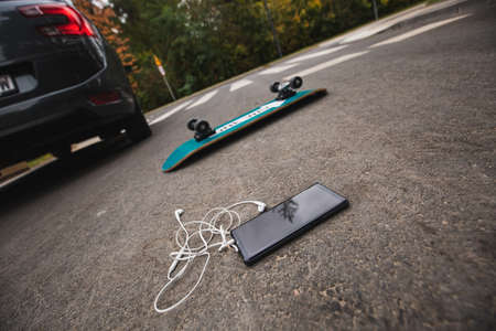 Skateboard and the phone after collision with a carの写真素材