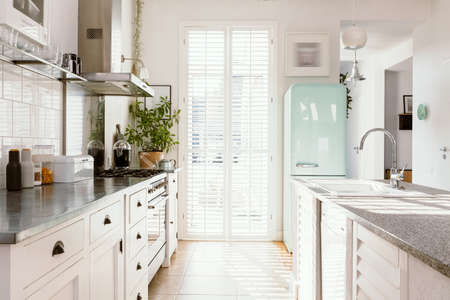 Bright kitchen interior with modern white furniture, pastel mint fridge and big floor to ceiling windowの写真素材