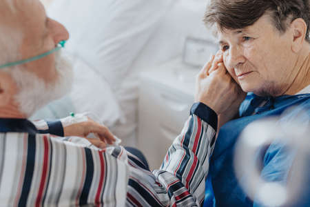 Senior supportive wife holding her dying husband's handの写真素材