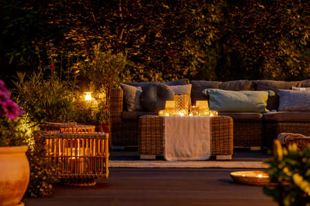 Trendy furniture, lights, lanterns and candles in the garden at nightの写真素材