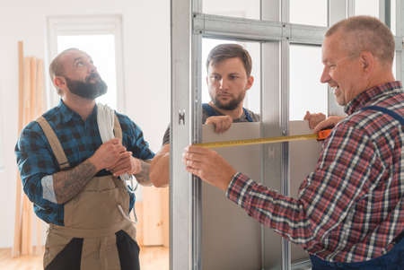Three builders in uniforms working in a team by house renovationの写真素材