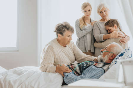 Senior man dying in the hospital visited by his loving familyの写真素材