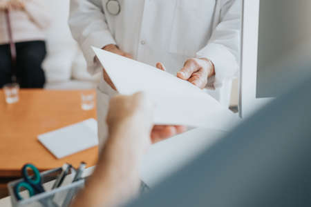 Close-up of nurse giving to older doctor patient's medical historyの写真素材