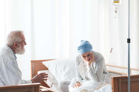 Older doctor sharing bad news with his sick worried patientの写真素材