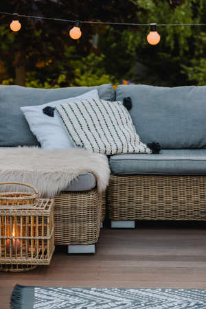 Wicker coffee table and sofa with pillows on the patio of beautiful gardenの写真素材