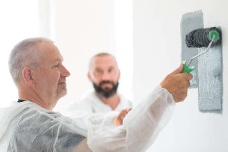 Closeup of renovation crew painting wall gray with painting rollの写真素材
