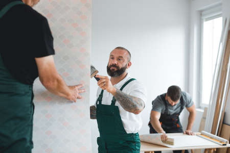 Renovation crew of three professional builders remodeling bright apartmentの写真素材