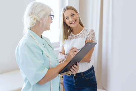Nutritionist with notes on a control appointment with her young clientの写真素材