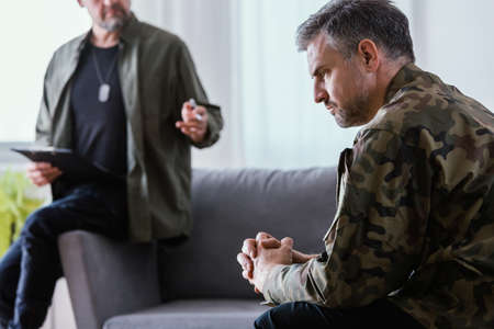 Middle aged man in army uniform healing his depression at psychotherapyの写真素材