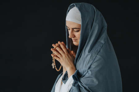 Mother of God praying with rosary on a black background