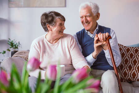 Senior happy couple sitting together on a couch in a nursing homeの写真素材