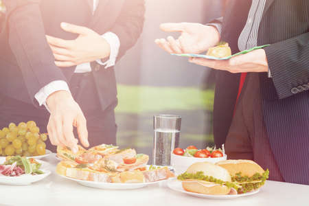 Bright photo of two businessmen during outdoor business lunchの写真素材