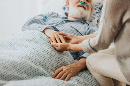 Close-up of older dying man holding his wife's handsの写真素材