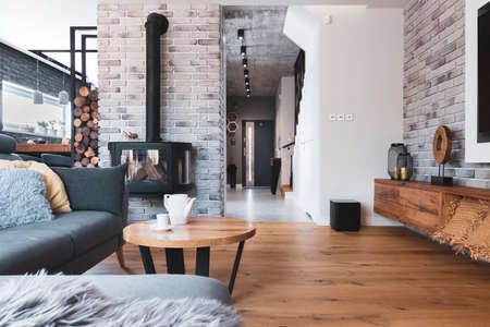 Stylish living room interior with wooden floor, brick wall and fireplaceの写真素材