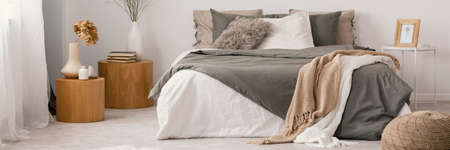 Real photo of a natural bedroom interior with a double bed and wooden bedside tablesの写真素材