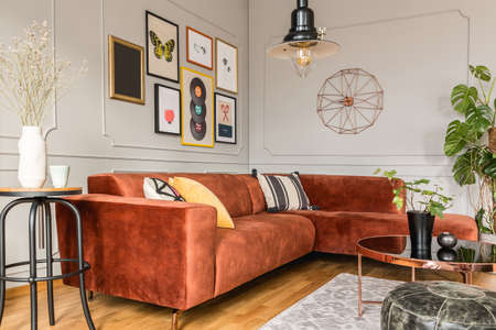 Stylish living room interior with comfortable couch, coffee table, flowers and postersの写真素材