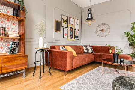 Eclectic living room interior with comfortable velvet corner sofa with pillowsの写真素材