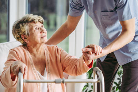 Young male nurse helping an older woman in nursing homeの写真素材