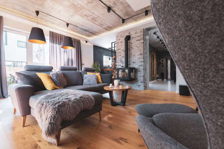 Gray couch with pillows next to modern fireplace in stylish living room interiorの写真素材