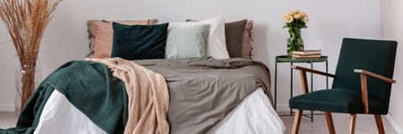 Real photo of a scandi bedroom interior with a bed, spikes and armchairの写真素材