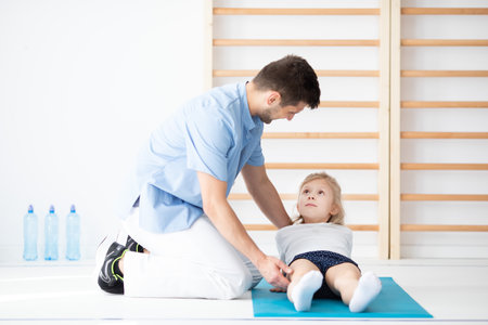 Young physical therapist exercising with a girl with spine problemsの写真素材