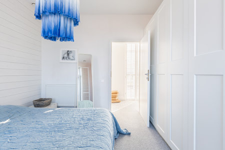 Stylish modern white and blue chandelier in trendy spacious bedroom with king size bedの写真素材