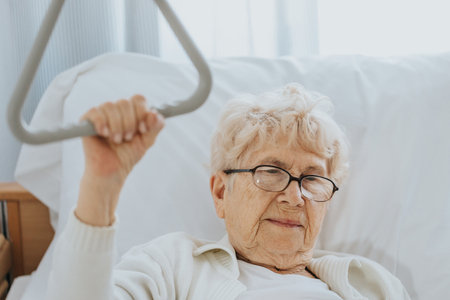 Sick older woman trying to stand up using a handleの写真素材