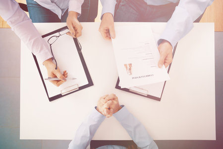 Top view of white table and people with legal pad and cv during recruitment interviewの写真素材