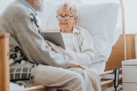 Senior woman reading a book and spending time with her husband in nursing homeの写真素材