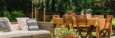 Green pant on wicker coffee table in front of Dining table covered with orange tablecloth standing...
