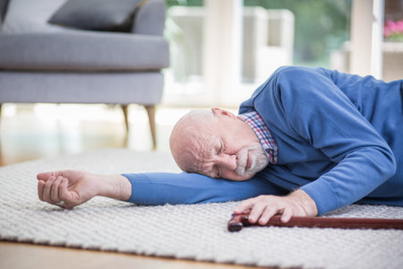 Senior man in blue sweater lying on the floor of his apartmentの写真素材
