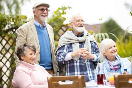 Happy senior friends during party at beautiful garden of suburban villaの写真素材